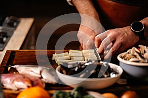 Cook chopping celery on cutting board surrounded by a variety of ingredients.