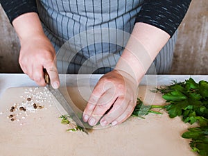 Cook chopping potherbs on wooden cutting board