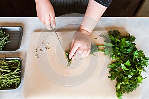 Cook chopping potherbs on wooden desk