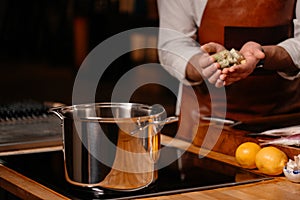 Cook cooking ingredients in a large pot in a kitchen with an array of a equipment