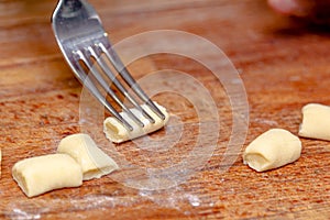 The cook correctly prepares the traditional Italian gnocchi dish with a fork