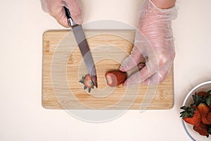 the cook cuts off the tails of strawberries on a wooden board close-up of hands