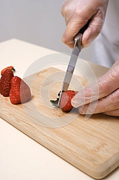 the cook cuts off the tails of strawberries on a wooden board close-up of hands