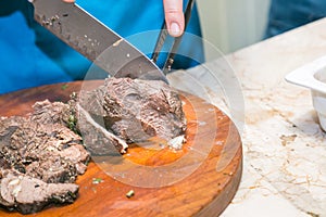 Cook cuts roasted beef meat. The concept of cooking