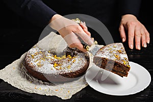 A cook is cutting a chocolate cake with a knife