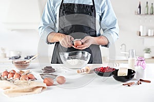 A cook with eggs on a rustic kitchen against the background of men`s hands