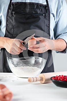 A cook with eggs on a rustic kitchen against the background of men`s hands