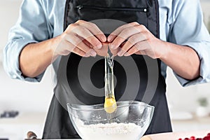 A cook with eggs on a rustic kitchen against the background of men`s hands