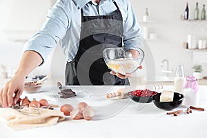 A cook with eggs on a rustic kitchen against the background of men`s hands