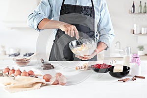 A cook with eggs on a rustic kitchen against the background of men`s hands