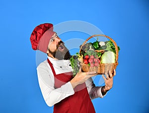 Cook with excited face in burgundy uniform holds vegetables