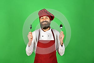 Cook with excited face holds spoon and fork