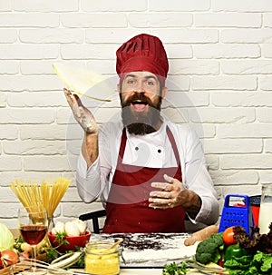 Cook with excited face in uniform sits by table