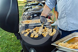 Cook flips grilled chicken kebabs in summer outdoors