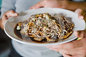 A cook and a food reviewer are showcasing a dish of pempek lenggang with a very close-up shot photo