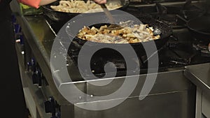 Cook fries pieces of chicken fillet meat in a frying pan or skillet in restaurant kitchen on gas stove in slow motion