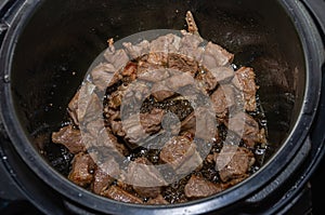 The cook fries pieces of lamb meat in a pan