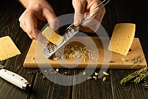 The cook grates Ukrainian cheese to prepare a salad for lunch. Concept of preparing a cheese dish on the kitchen table