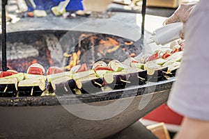 Cook hand preparing vegetables on grill plate on backyard grill, flame, smoke. Picnic, Grilled food