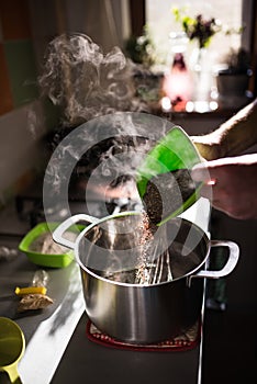 Cook hands adding rye malt to a kettle