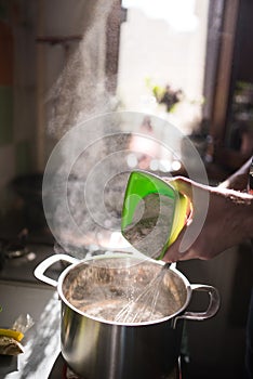 Cook hands adding whole wheat flour to a kettle