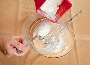 Cook hands adds flour into dish