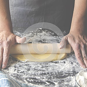 Cook hands kneading dough, sprinkling piece of dough with white wheat flour