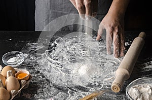 Cook hands kneading dough, sprinkling piece of dough with white wheat flour