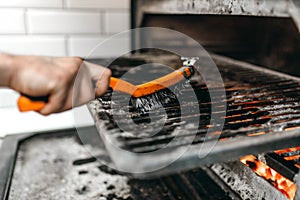 Cook hands with metal brush clean the grill oven