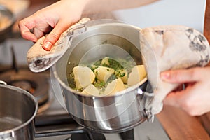 Cook holds pan with boiled potatoes