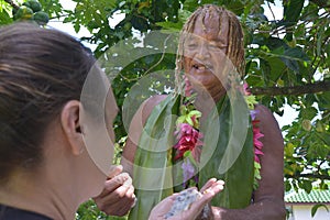 Cook Islander explains to a tourist woman about the Noni fruits