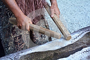 Cook Islander man plays on a large wooden log Pate drum instrument