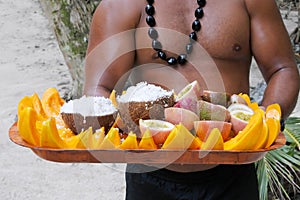 Cook Islander man serves coconut and papaya fruit on a tray in R