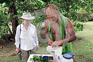 Cook Islander showing tourist woman how to prepare a herbal dri