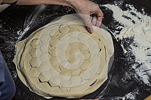 Cook kneads dough on dumplings with minced meat on a special form