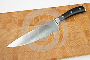 Cook Knife on the wooden endgrain cutting board above white background