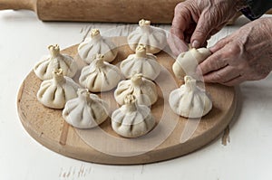 Cook making khinkali, dumplings, meat in the dough cooking with hands.