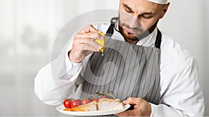 Cook Man Plating Salmon Steak Squeezing Lemon Standing In Kitchen