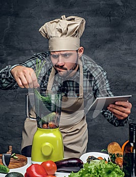 A cook man preparing vegetable cocktail in a blender.