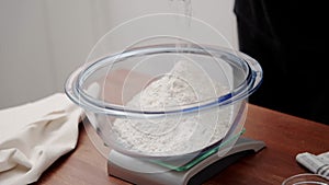 The cook measures flour for baking bread. the cook kneads the dough according to the recipe