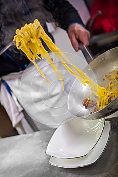 A cook while pouring pasta in dish