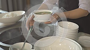 Cook pouring soup in bowl in buffet while lunch in all inclusive resort hotel restaurant. Restaurant food for