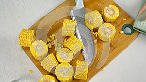 Cook, prepare, cut on pieces yellow fresh corn on wooden board on kitchen.
