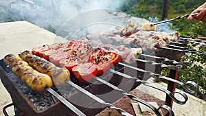 The cook prepares barbecue in the village. Pork meat on fire. Red tomatoes, yellow shorties and pork meat on the fire. Flight dish