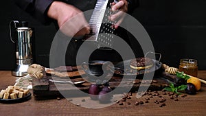 Cook prepares, chocolate on a grater. Close-up video shooting, dark background