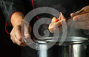 The cook prepares delicious shrimp or prawn in a pot in the restaurant kitchen. Cooking seafood, healthy vegetarian food and meal