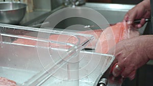 A cook prepares fillets of salmon for grilling