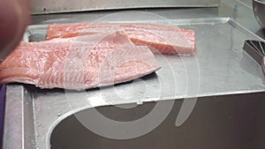 A cook prepares fillets of salmon for grilling