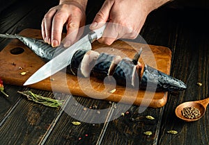 The cook prepares fresh mackerel in the kitchen. Before baking, the fish must be cut into small pieces. Fish diet idea