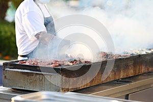 Cook prepares meat on coals in the open air